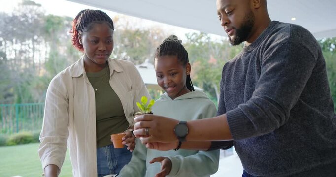 African American family arranging pots at patio potting seedlings and teaching child gardening