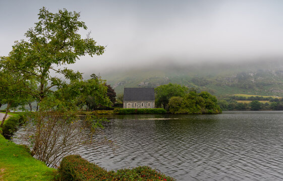 St. Finbarr oratory church on a lake island surrounded by fog and green hills. Gougane Barra county Cork Ireland