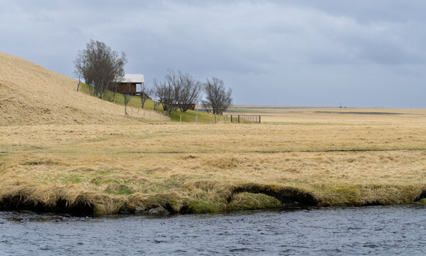 Farm house farmhouse standing on a hill above a river with a wide rural icelandic landscape Iceland