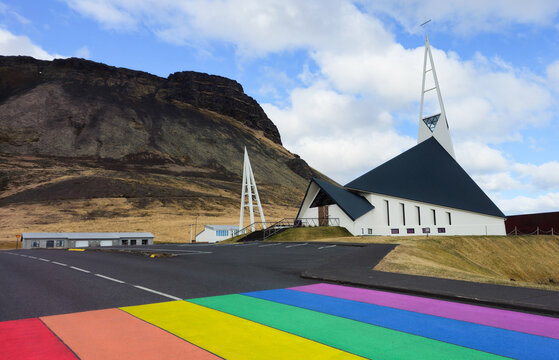 Modern olafsvikurkirkja church standing by a vibrant rainbow crosswalk in olafsvik, iceland. Place of worship Icelandic churches