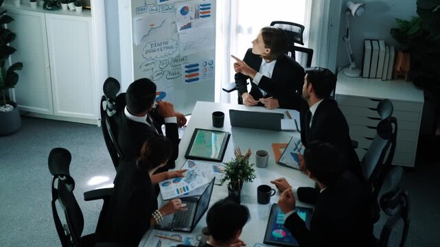 Top view of smart manager project pointing at whiteboard with mind map and financial graph and explain marketing idea while diverse investors listening and analyze stock investment chart. Directorate.