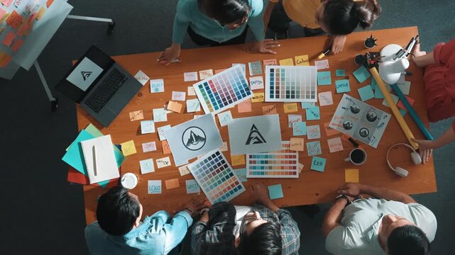 Top down view of smart designer explain and brainstorming idea for logo design and writing concept. Aerial view of business people discuss and talking while using sticky notes sharing idea. Symposium.