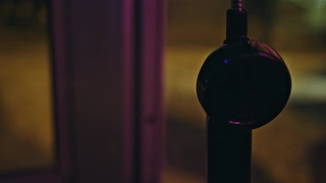 Payphone handset closeup night city street. Blurred woman walking background.