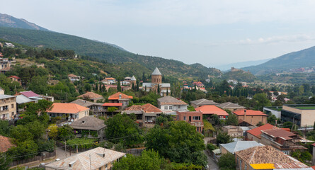 Fototapeta premium Scenic landscape of Mtskheta with a historic church, red-roofed houses, and mountain ranges