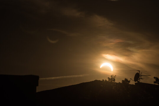 Partial solar eclipse forming a glowing sun crescent over city rooftop silhouettes at night in Kiel Germany Baltic Sea 2026 