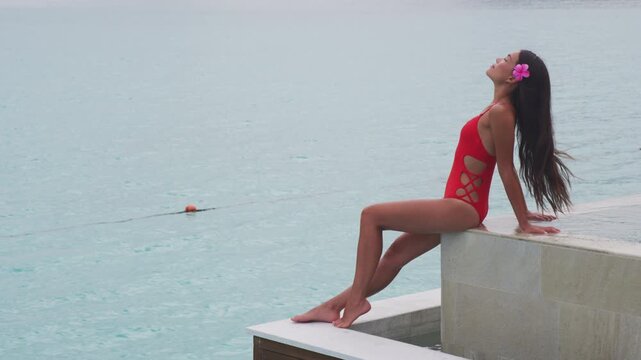 Spa woman after laser treatment with shaved legs. Luxury resort travel vacation natural beauty picture by idyllic overwater bungalow villa. Woman relaxing by infinity pool. Social media influencer