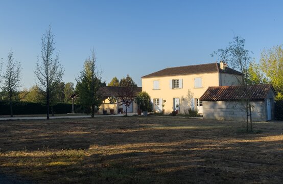 peaceful rural landscape with country house and trees in side view, beige and brown tones, serene countryside scene, real estate and vacation rentals context, brick, wood, metal materials.