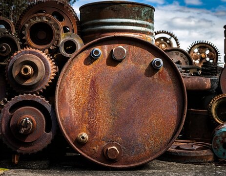 weathered industrial barrel or oil drum sits beside heavy mechanical cogs and machinery this vintage junk pile features a distressed stencil look with high contrast textures