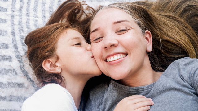 Happy mother and daughter hugging and kiss each other and having fun at home - Family love concept - Main focus on child eye