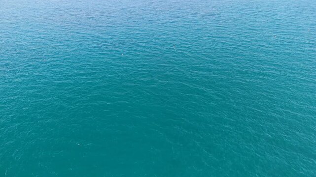 Aerial top down view of turquoise blue sea surface with gentle ripples on open water