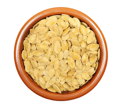 Pile roasted pumpkin seeds with salt in clay pot isolated on white background, top view
