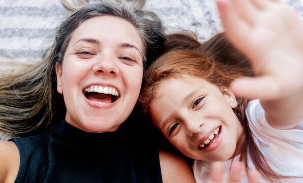 Latin mother and child daughter making selfie or video call to father or family in living room floor. Technology, generation, connection, motherhood and authenticity concept