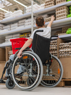 A Caucasian woman in a wheelchair shopping in a supermarket.