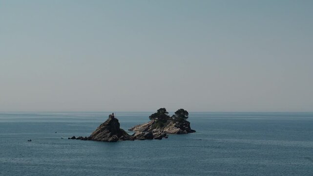 Katic and Sveta Nedjelja islands rise from the Adriatic Sea near Petrovac, Montenegro. Rocky islets and chapel create a scenic coastal travel landmark