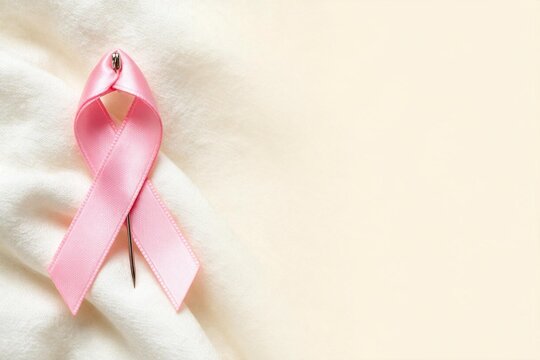 Pink awareness ribbon on a soft fabric background  