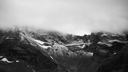 Obraz premium Clouds cover the mountain peaks of the Ankogel Group. Snow can be seen on the slopes. This scene captures the rugged nature of the Eastern Alps during a cloudy day.