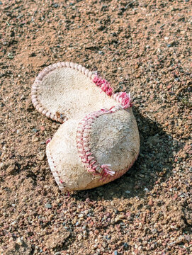 Worn Baseball Cover Lying on Dirt Warning Track at Baseball Field