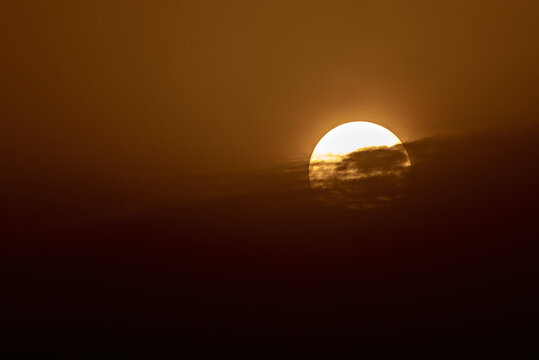 View of the sun setting behind clouds in the golden sky in Jahanian, Pakistan.
