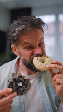 A man eating two donuts simultaneously with delight. Sugar addiction. Slow