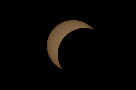 partial solar eclipse over dark yellow sky at night, mysterious and scientific astronomical view of sun and moon in blackness, serene and dramatic natural phenomenon, educational resource.