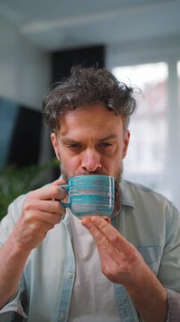 Happy man drinking coffee at relaxed home environment closeup.