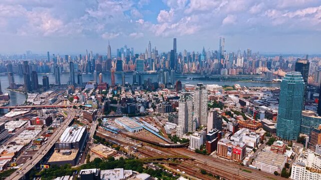 Footage over the buildings and train yards in Long Island City, Queens. Midtown Manhattan skyline in the backdrop. New York City, USA.