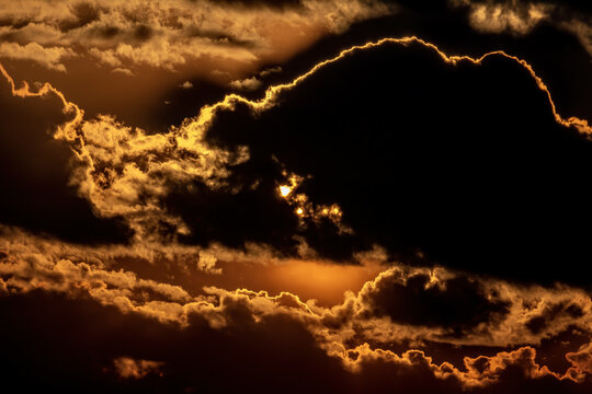 View of dramatic golden clouds illuminated by the setting sun against a dark sky in Jahanian, Pakistan.