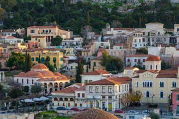 Obraz premium Elevated view of the historic Plaka neighborhood in Athens, Greece, featuring traditional colorful houses and the Fethiye Mosque with its multiple domes at golden hour.