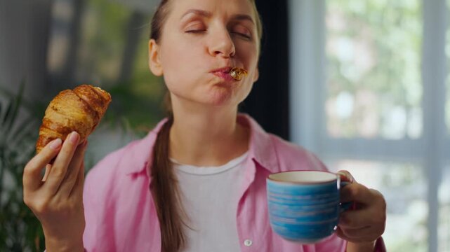 Woman enjoying a fresh croissant and coffee for breakfast.