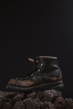 old leather hiking boot standing on rock stones