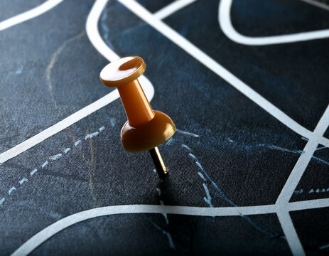 close up view of a dark surface with winding pathways marked with pushpins showcasing route guidance and directional choices