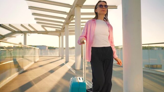 Woman confidently pulling a suitcase in an airport terminal.