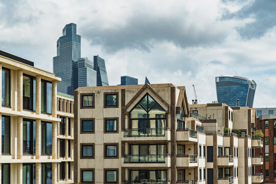 View of modern residential architecture in the foreground with the iconic London skyline and skyscrapers in the background under a cloudy sky in London, England, United Kingdom.