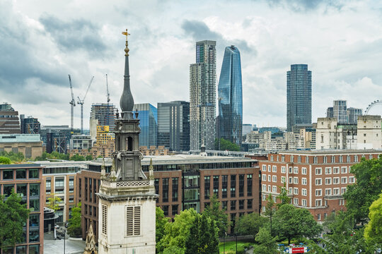 View of the historic St. Magnus-the-Martyr church tower in the foreground set against the modern skyscrapers of the City of London skyline in London, England, United Kingdom.