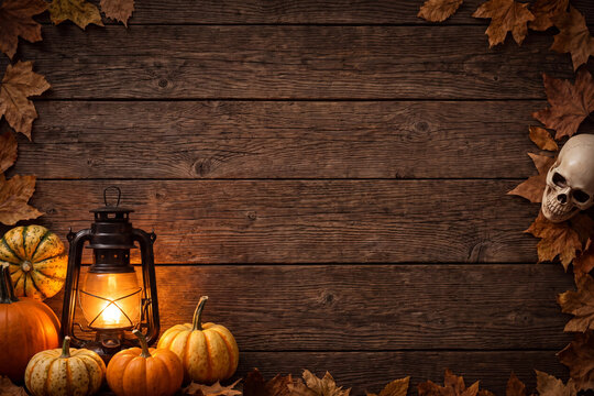 Autumn halloween wooden background with pumpkins lantern skull and fallen leaves rustic seasonal decoration