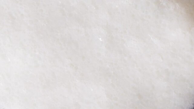 Creamy white froth and bubbles on blended milk drink surface, full-frame macro texture background