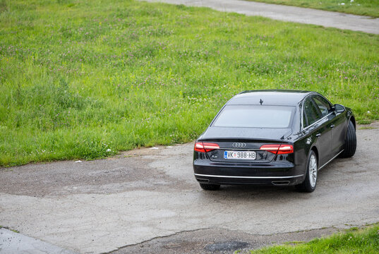 Luxury Black Audi A8 Sedan Rear View Parked On Wet Rural Road Near Green Field