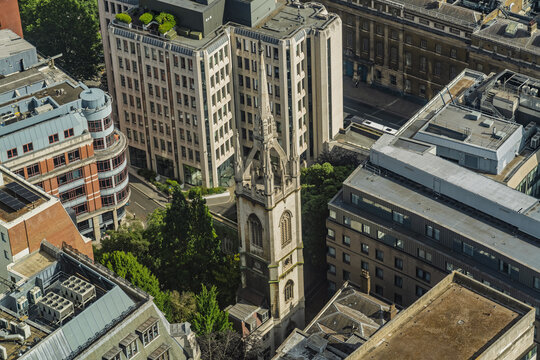 View of the historic spire of St Bride's Church surrounded by modern office buildings and urban rooftops in London, England, United Kingdom.