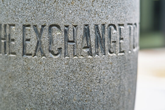 View of the carved stone inscription The Exchange on a textured granite pillar in London, England, United Kingdom.