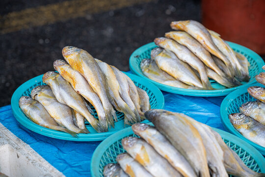 Fresh yellow croakers displayed on baskets at traditional fish market in South Korea.