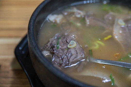 Hot ox head soup with tender beef in earthenware bowl at traditional market restaurant in South Korea.