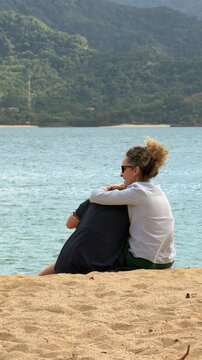 Mother and daughter enjoying family time at Feiticeira Beach in Ilhabela, with the beaches of S&atilde;o Sebasti&atilde;o in the background.