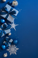 Fototapeta premium Blue Christmas gift vertical composition with ribbons, ornaments and decorations for Merry Christmas and Happy New Year on night background