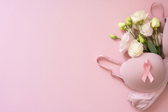 Pink bra with awareness ribbon and flowers on soft pink background for Breast Cancer Awareness month
