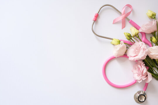 Pink stethoscope and ribbon with lisianthus flowers on white background for Breast Cancer Awareness Month