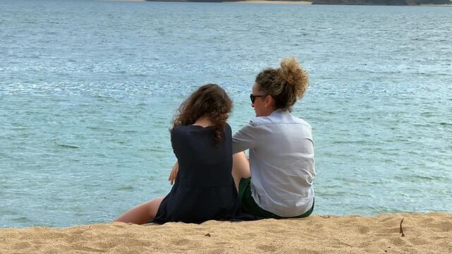 Mother and daughter enjoying family time at Feiticeira Beach in Ilhabela, with the beaches of S&atilde;o Sebasti&atilde;o in the background.