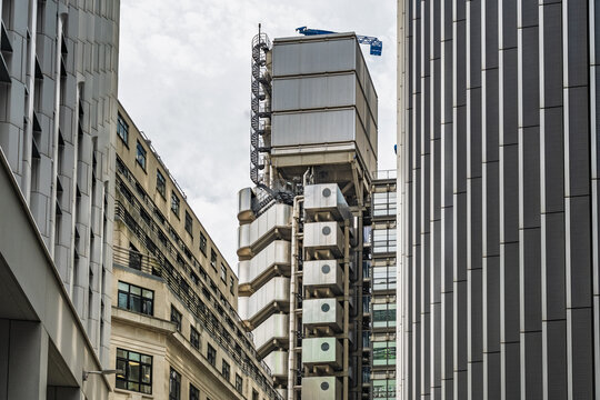 View of the iconic Lloyd's building with its distinctive external service ducts and metallic facade, framed by modern office buildings in London, England, United Kingdom.