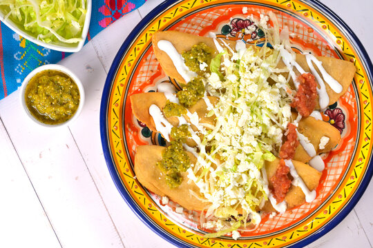 Overhead view of deliciousMexican molotes with lettuce and red and green salsas
