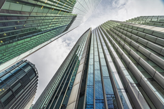 View of modern glass skyscrapers reaching towards a cloudy sky in the financial district of London, England, United Kingdom.