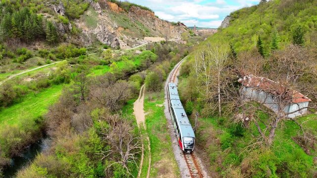 Aerial 4K Drone View of Passenger Train Passing Through Green Zemen Gorge Canyon in Bulgaria